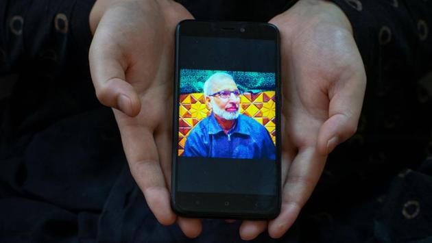 Khushboo,26, a student, shows a picture of her father Shakeel Ahmad Baba, a government employee, who died of Covid-19, in Srinagar on September 24. “Our lives changed drastically after my father passed away, he was a loving father, a decision maker. A day before his death I spoke to him on the phone and he told me to pray for him. His death left a great void in our entire family,” Khushboo told Reuters. (Sanna Irshad Mattoo / REUTERS)