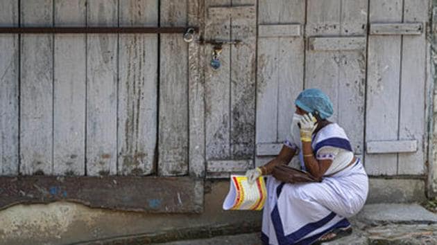 An Indian health worker talks on her mobile phone while waiting for a Covid-19 positive patient in Guwahati.(AP)