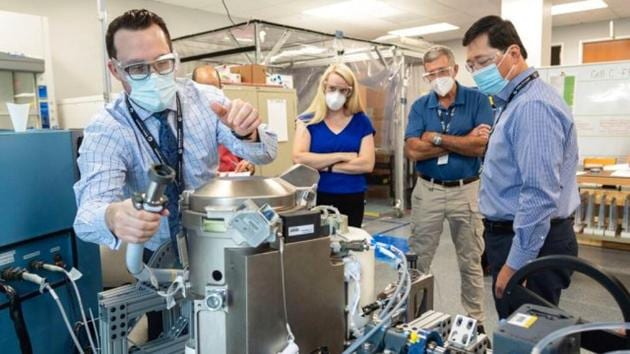 In this June 18, 2020 photo provided by NASA, astronaut Kate Rubins, center, and support personnel review the Universal Waste Management System, a low-gravity space toilet, in Houston. The new device is scheduled to be delivered to the International Space Station on Oct. 1, 2020.(Associated Press)