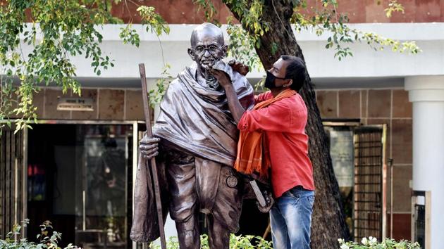 A worker cleans the statue of Mahatma Gandhi on the eve of Gandhi Jayanti at Rajghat in New Delhi on Thursday. (ANI Photo)