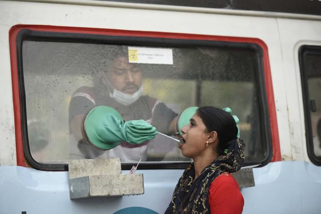 A health worker collects a swab sample from a woman for reverse transcription-polymerase chain reaction (RT-PCR) based coronavirus testing in Gurugram on Thursday.(Parveen Kumar/HT Photo)