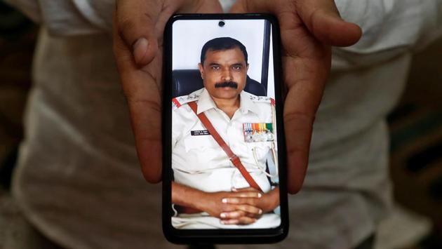 Rahul Adhav,26, a pharmacist, shows a picture of his father Bhaginath Jagannath Adhav, a police officer, who died of Covid-19, in Mumbai on September 28. “Life has become lonely since my father passed away. He did his best while on duty urging people to maintain social distance. I request people to co-operate with the police. I also request the government to provide financial support to families of police who died while serving in the pandemic,” Adhav told Reuters. (Francis Mascarenhas / REUTERS)