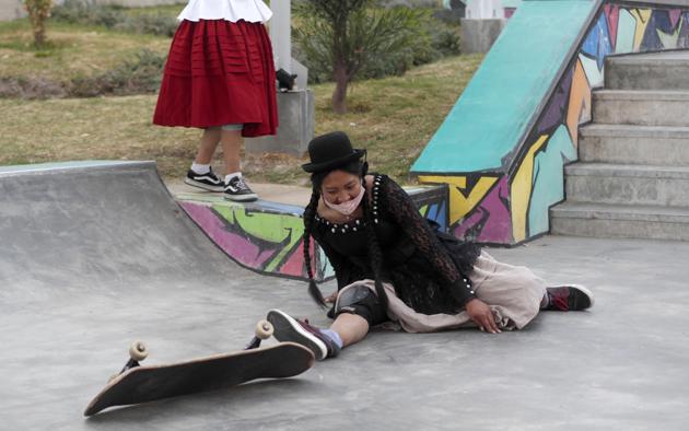 Aide Choque, wearing a mask amid the COVID-19 pandemic and dressed as a "Cholita" falls off her skateboard during a youth talent show in La Paz, Bolivia, Wednesday, Sept. 30, 2020. (AP)
