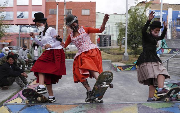 Milenda Limachi, left, Yanira Villarreal, center, and Ayde Choque, wearing masks amid the COVID-19 pandemic and dressed as a "Cholitas" ride their skateboards during a youth talent show in La Paz, Bolivia, Wednesday, Sept. 30, 2020. (AP)