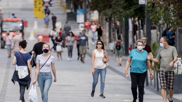 People wear face masks as they walk along a street in Montreal, Canada.(AP)