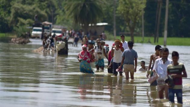 Villagers wade through a flooded road after heavy rainfall, in Hojai district of Assam on September 29.(PTI)