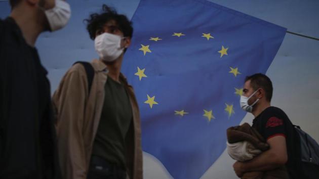 Backdropped by a poster with a European Union flag, people, wearing masks to help protect against the spread of coronavirus, walk in Istanbul. Image used for representational purpose.(AP)