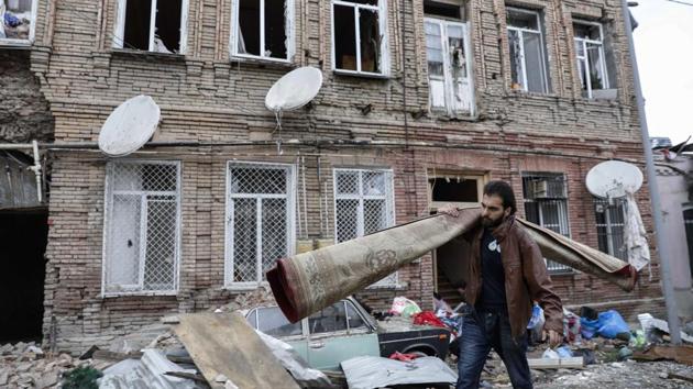 A person carries a carpet as he walks past buildings in a residential area in Ganja, Azerbaijan, damaged by shelling by Armenian forces, Monday, Oct. 5, 2020. (AP) A person carries a carpet as he walks past buildings in a residential area in Ganja, Azerbaijan, damaged by shelling by Armenian forces, Monday, Oct. 5, 2020. (AP)
