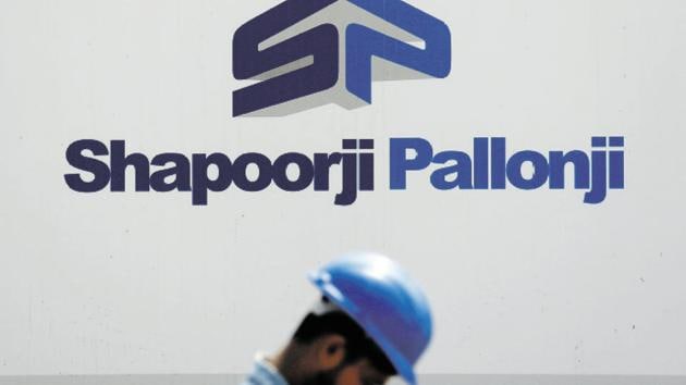 A construction worker walks past a hoarding of Indian conglomerate Shapoorji Pallonji Group on the outskirts of Mumbai.(Reuters File Photo)