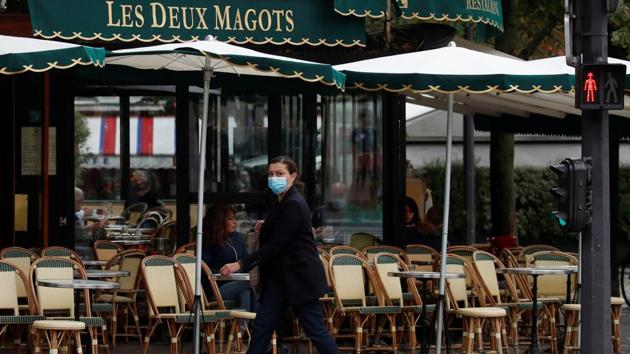 A woman wearing a protective face mask walks past the cafe and restaurant Les Deux Magots in Paris, during the announcement of new Covid restrictions by Paris authorities as the coronavirus disease outbreak continues in France. (REUTERS) A woman wearing a protective face mask walks past the cafe and restaurant Les Deux Magots in Paris, during the announcement of new Covid restrictions by Paris authorities as the coronavirus disease outbreak continues in France. (REUTERS)