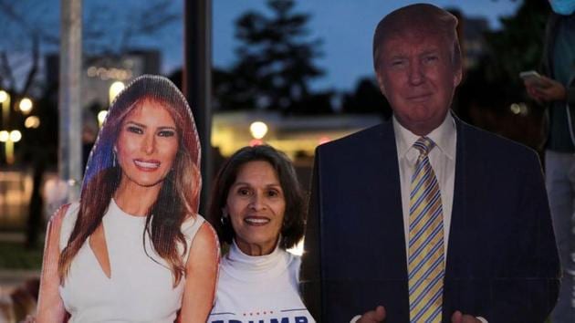 A supporter stands in between cardboard cutouts of First Lady Melania Trump and US President Donald Trump, outside of the Walter Reed National Military Medical Center, where President Trump is being treated for the coronavirus disease (Covid-19) in Bethesda, Maryland, US.(REUTERS)
