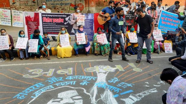 Demonstrators hold placards and stand near a mural on a street as they protest against the alleged gang-rape of a 19-year-old Dalit woman in Hathras (UP) in New Delhi on Sunday.(PTI Photo)