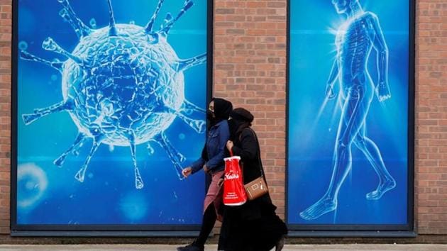 People walk past an illustration of a virus outside a regional science centre, as the city and surrounding areas face local restrictions in an effort to avoid a local lockdown being forced upon the region, amid the coronavirus disease outbreak, in Oldham, Britain. (REUTERS) People walk past an illustration of a virus outside a regional science centre, as the city and surrounding areas face local restrictions in an effort to avoid a local lockdown being forced upon the region, amid the coronavirus disease outbreak, in Oldham, Britain. (REUTERS)