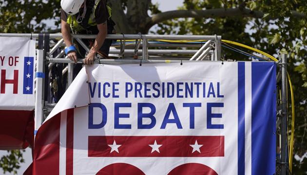 A worker hangs a banner as preparations take place for the vice presidential debate outside Kingsbury Hall at the University of Utah, Monday.(AP Photo)