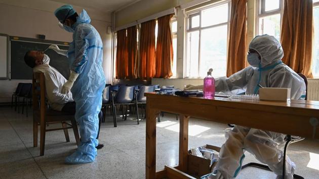 A medical worker collects a swab sample from a staff member of the Burnhall school inside a classroom, in Srinagar on October 5. The Indian Council of Medical Research (ICMR) dashboard shows that 11,99,857 samples were tested for Covid-19 on October 6 and 8,22,71,654 samples have been tested in the country till date. (Tauseef Mustafa / AFP)