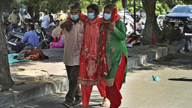 A woman (centre) is assisted outside a government- run hospital in Jammu on October 5. The number of active cases, which shows a country’s disease burden nationally, stands at 907,883. India has for two straight weeks recorded less than 1 million active cases which contribute only 14.1% to the Covid-19 positive caseload. (Channi Anand / AP)