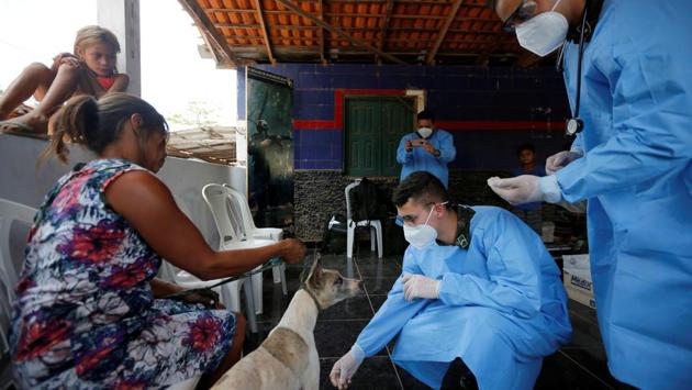 Members of the Brazilian Armed Forces veterinarian team examine the dog of a woman from the indigenous Guajajara ethnic group, in the village of Urucu Jurua on October 3. (Adriano Machado / REUTERS)