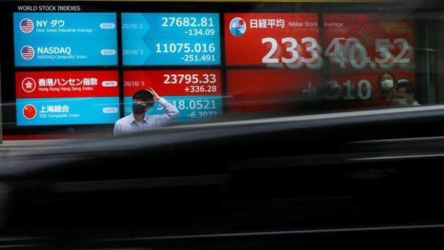 A passersby wearing a protective face mask stands in front of a screen displaying Nikkei share average and world stock indexes outside a brokerage. (REUTERS) A passersby wearing a protective face mask stands in front of a screen displaying Nikkei share average and world stock indexes outside a brokerage. (REUTERS)