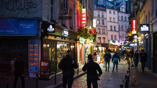 Police patrol near illuminated take away food outlets as new coronavirus measures come into force for bars and restaurants, at night in Paris, France on October 6, 2020. (Bloomberg Photo) Police patrol near illuminated take away food outlets as new coronavirus measures come into force for bars and restaurants, at night in Paris, France on October 6, 2020. (Bloomberg Photo)