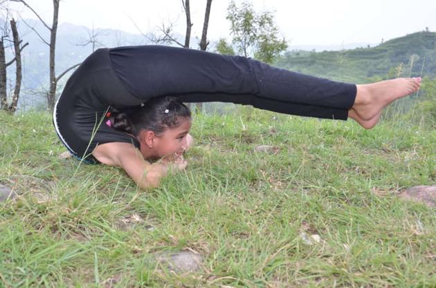 Nidhi Dogra performing a yoga asana outside her house in Hamirpur district.(HT Photo)