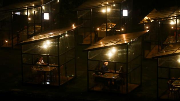 People sit inside protection booths at the Sushi das Artes restaurant in Rio de Janeiro on October 6. Health officials also say that people shunning isolation and taking to public activities is a pressing concern as campaigning mayors are allowing bars, restaurants and movie theatres to reopen - encouraging people to emerge from quarantine. (Pilar Olivares / Reuters)