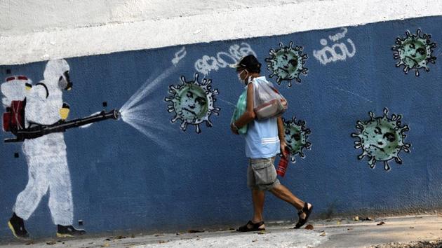 A man walks next to a graffiti depicting a cleaner in protective gear spraying viruses with the face of Brazil’s President Jair Bolsonaro in Rio de Janeiro on October 7. According to John Hopkins University’s tally, Brazil surpassed 5 million confirmed coronavirus cases on October 7 to become world’s third hardest coronavirus-hit country. (Ricardo Moraes / Reuters)