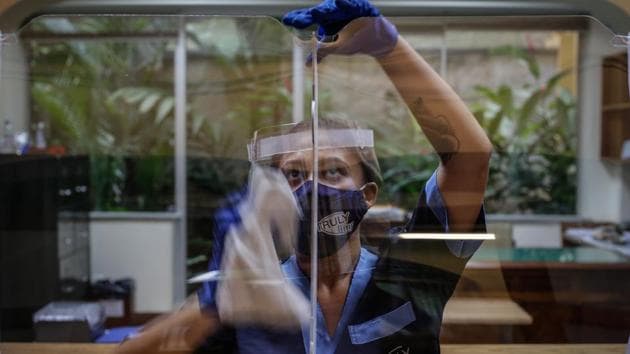 An employee wearing a protective mask and face shield disinfectants the teacher’s lounge at a school in Rio de Janeiro on October 5. “Mayors running for re-election have no interest in imposing any kind of lockdown or restrictions, their incentive is to roll back lockdown measures,” Miguel Lago, Executive director of Brazil’s Institute for Health Policy Studies which advises public health officials told AP. (Andre Coelho / Bloomberg)
