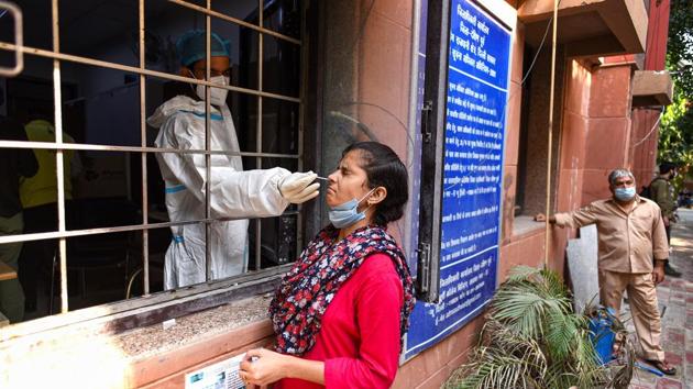A healthcare worker collects swab sample from a woman for coronavirus testing, at New Delhi’s Amar Colony on Friday.(Biplov Bhuyan/HT Photo)