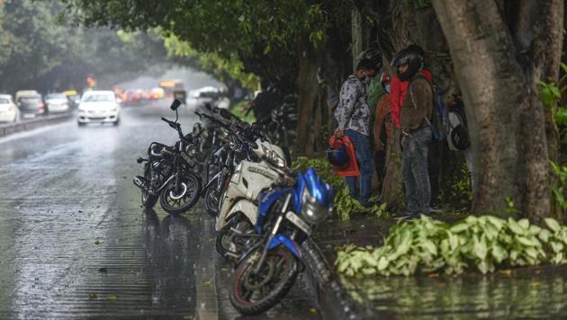 People take shelter under a tree while it rains, at Mathura Road in New Delhi.(Biplov Bhuyan/HT PHOTO)