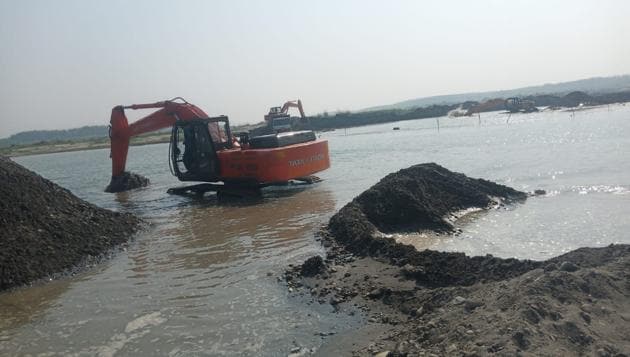 Pictures and videos released by river activists and residents of the village purportedly show contractors using heavy machines and trucks to carry out mining in the flowing river.(HT PHOTO)