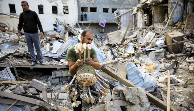 A man carries a chandelier away from the ruins at the blast site hit by a rocket during the fighting over the breakaway region of Nagorno-Karabakh in the city of Ganja, Azerbaijan (REUTERS/Umit Bektas)