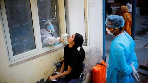 A health worker in personal protective equipment (PPE) collects a sample using a swab from a person at a local health centre to conduct tests for the coronavirus disease amid the spread of the disease, in New Delhi.(REUTERS)