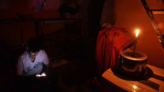 A person using a mobile phone in a candle-lit room during the power outage, at Thane in Mumbai on October 12. The widespread power cut also led to a rocky start for those beginning the week working from home. With no access to power backup or WiFi networks, people working remotely were forced to postpone meetings and deadlines. (Praful Gangurde / HT Photo)