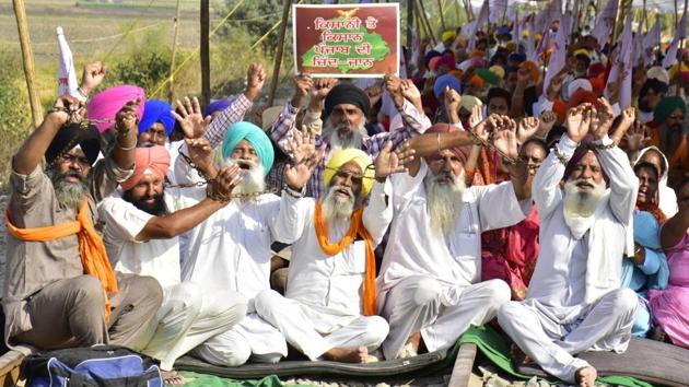 Farmers raising slogans on rail tracks with hands tied in chains as part of their rail blockade agitation against the new farm laws, at Devi Dass Pura in Amritsar on Monday.(Sameer Sehgal/HT)