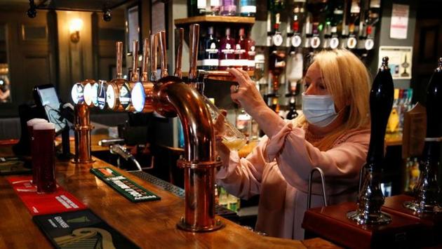 A woman wearing a face mask seen at work at the Grapes pub in Liverpool on October 12. The British government has announced a support package to pay two-thirds of the salaries of employees of companies that are told to close, but many in the pub and restaurant sector say that is not enough to save already struggling businesses. (Phil Noble / REUTERS)