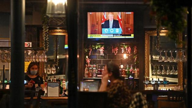 Visitors watch the telecast of Britain Prime Minister Boris Johnson’s address on new local lockdown measures in wake of a second wave of Covid-19, at William Gladstone pub in Liverpool on October 12. The British government categorised England into three tiers of coronavirus risk on October 12 in a bid to slow a resurgent outbreak, putting the northern city of Liverpool into the highest-risk category and shutting its pubs, gyms and betting shops. (paul Ellis / AFP)