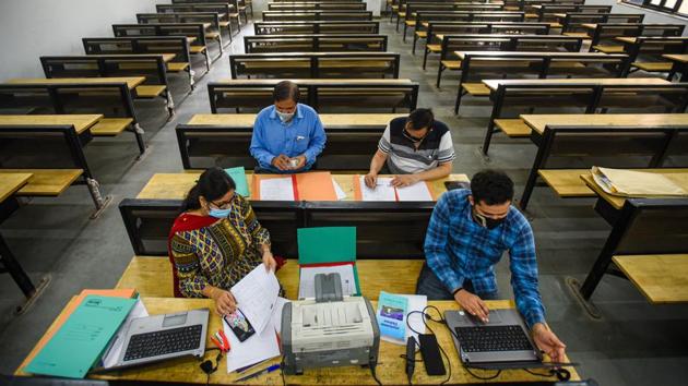 Faculty members at work on the first day of admissions, at Ramjas College in New Delhi on October 12. Colleges adapted differently to the admission process being taken completely online. Ramjas has set up 22 rooms, each for every department, for admission work. Every time a student applies for a course, the teachers on duty receive a notification. They then take printouts of the application to calculate the ‘best of four’ and verify documents. (Amal KS / HT Photo)