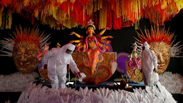 People wearing personal protective equipment (PPE) sanitise a "pandal" or a temporary platform, next to an idol of Hindu goddess Durga for the upcoming of Durga Puja festival, amidst the spread of the coronavirus disease in Kolkata.(REUTERS)