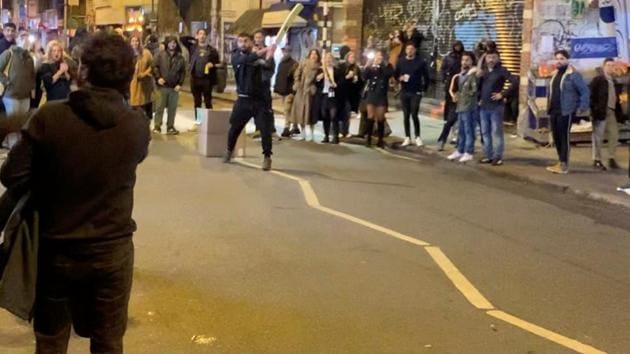 An impromptu cricket game draws crowds onto the streets after pubs and bars shut to curb the spread of COVID-19 in Peckham, London, Britain.(@JAMESJONESFILM via REUTERS)