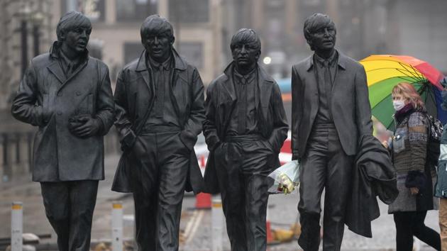 A commuter wearing a face mask passes a statue of The Beatles in Liverpool on October 12. Liverpool was the only area put into the “very high” risk category on October 12, but Johnson said authorities were still talking with other local leaders across the north of England, AP reported. (Jon Super / AP)