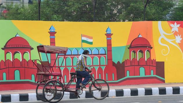 A rickshaw puller rides past a mural depicting Red Fort along a road near Akshardham Temple, in New Delhi.(PTI)