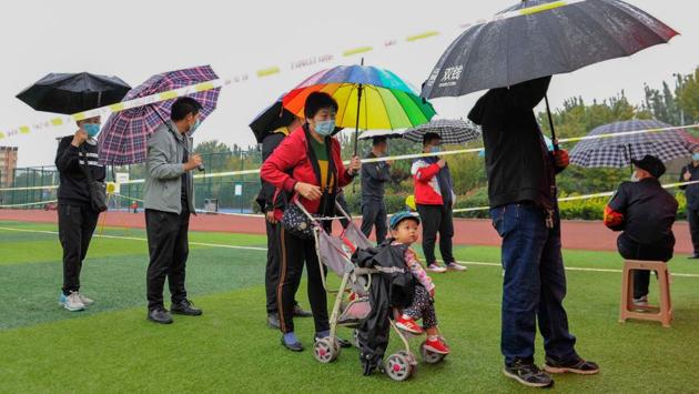 People line up in the rain to be tested for the Covid-19 as part of a mass testing program following a new outbreak in Qingdao, China on October 14. Chinese officials intend to test the entire city--around 9.4 million people--by October 15, after a handful of cases were detected on October 11. (AFP)