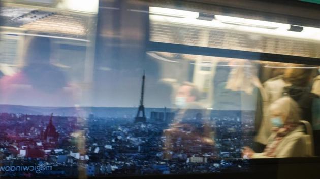 Commuters in a metro train pass a poster showing the Eiffel Tower and city skyline at Champs-Elysees–Clemenceau metro station in Paris, France on October 14. French President Emmanuel Macron in a prime-time TV interview on October 14, announced night curfew in Paris and eight other major cities of France for six weeks. The curfew restrictions begin from October 17. (Nathan Laine / Bloomberg)