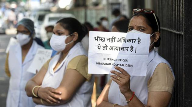 A medical worker shows a banner during protest to demanding their unpaid salary of four months, outside Hindu Rao Hospital, at Malka Ganj, in New Delhi.(Biplov Bhuyan/HT PHOTO)