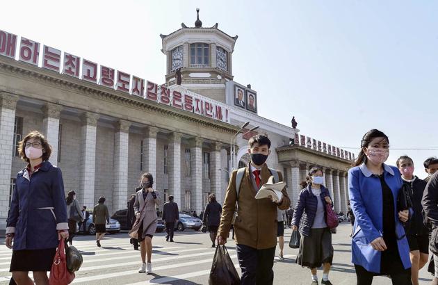 People wearing protective face masks walk amid concerns over the Covid-19 in front of Pyongyang Station in Pyongyang(REUTERS)