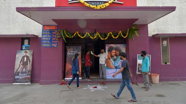 A movie goer (C) gets his temperature checked at the entrance of a cinema theatre in Bangalore on October 15. Show timings of the screenings will be staggered to avoid overcrowding. Advance bookings have also been made available for the purpose. (Manjunath Kiran / AFP)