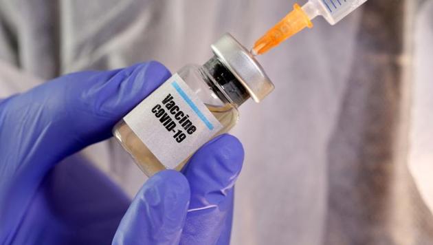 A woman holds a small bottle labeled with a "Vaccine Covid-19" sticker and a medical syringe in this illustration taken April 10, 2020. REUTERS/Dado Ruvic/Illustration