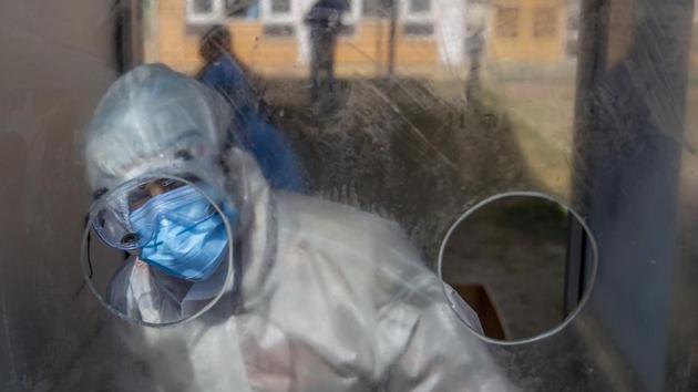 A health worker seen inside an enclosed kiosk while collecting swab samples to test for Covid-19 infection in Srinagar on October 14. The 55,342 cases that were reported on October 13 was the lowest single day increase in India in nearly two months. (Dar Yasin / AP)