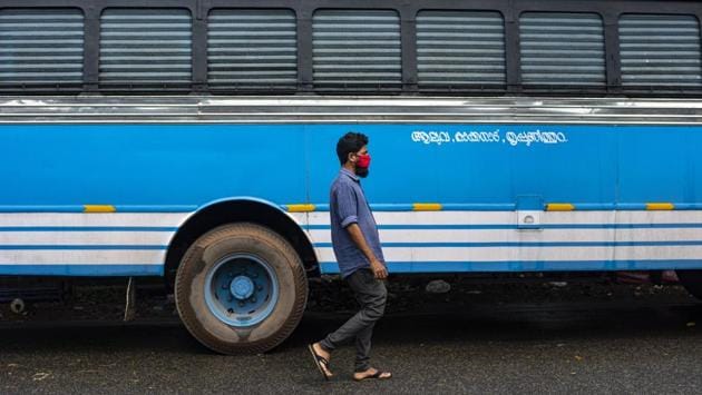A man wearing a face mask walks past a bus in Kochi on October 15. India crossed one million cases on July 17 and doubled those to two million in the next 21 days. Adding cases at an increasingly faster rate, it crossed the current seven million mark on October 11. (RS Iyer / AP)