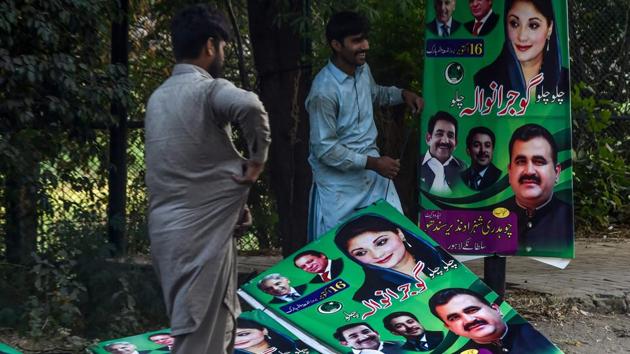 Workers hang posters of opposition party Pakistan Muslim League Nawaz (PML-N) on a street in Lahore on October 15.(AFP)